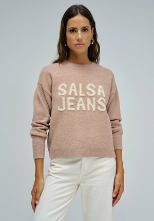 Suéter de punto rosa claro con "SALSA JEANS" en letras blancas difusas, con cuello redondo y puños acanalados. Combinado con pantalones blancos.