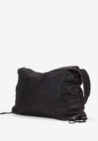 Bolso de hombro de piel en negro, con una gran forma rectangular, textura suave, correa ajustable y detalles de cuerda.