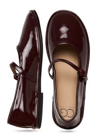 Bordeauxfarbene Lackleder-Mary-Jane-Schuhe mit runder Spitze, einem Riemen über dem Fuß und einer flachen schwarzen Sohle. Glatte Textur und minimale Details.