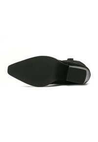 Zapato negro con suela de goma texturizada, punta afilada y un acabado mate elegante. Presenta un diseño minimalista y un tacón bajo.