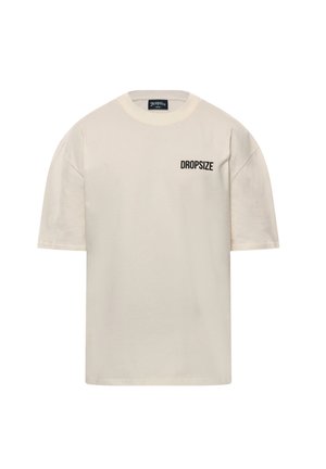 Crème t-shirt met korte mouwen gemaakt van katoen, met een ronde hals en de tekst "DROPSIZE" in het zwart op de linker borstzijde.