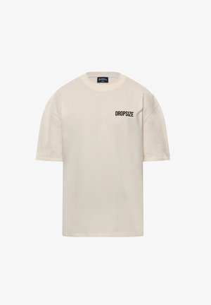 Cremefarbiges T-Shirt mit kurzen Ärmeln aus Baumwolle, mit rundem Ausschnitt und dem Text "DROPSIZE" in Schwarz auf der linken Brustseite.