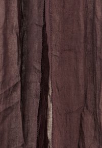 Tissu bourgogne foncé avec une finition texturée, présentant un bord brut et une subtile brillance, drapant en douces plis. Idéal pour des superpositions ou des accents de design.