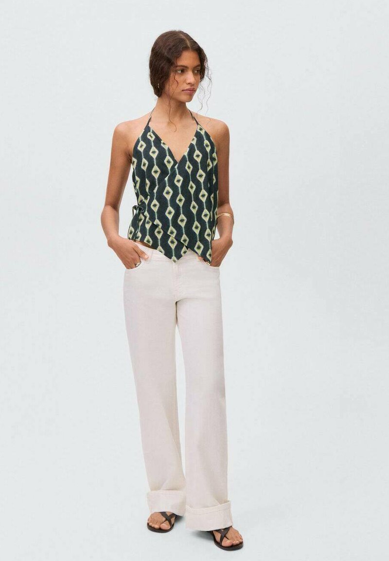 Top con colletto halter in tessuto verde scuro con un motivo a rombi crema. Abbinato a pantaloni larghi crema e sandali neri.
