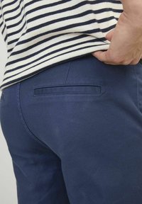 Navy blue pants with a textured fabric and a back pocket; worn with a striped, white and navy top. No visible fastenings or embellishments.