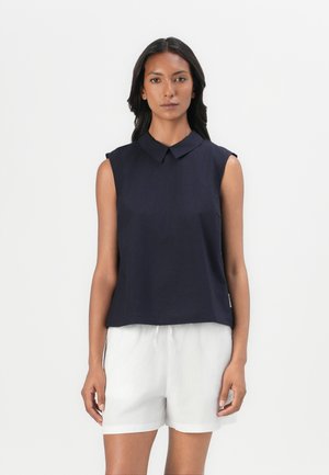 Navy blue sleeveless top with a collared neckline, made from a smooth fabric. Paired with white drawstring shorts.