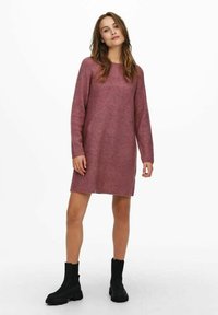 Rosa stickad klänning med långa ärmar, rak skärning, diagonalt ribbat mönster och rundad halsringning, kombinerad med svarta ankelskor.