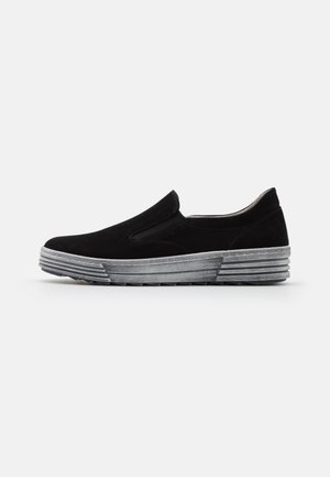 Chaussure noire à enfiler avec tige en daim et semelle épaisse en caoutchouc gris texturé, vue de profil sur un fond blanc uni.