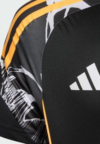 Čierne športové tričko s žltými pruhmi a abstraktnými bielymi vzormi. Obsahuje ergonomické švy a výrazné bílé logo na boku.