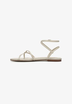 Beige sandalen met dunne bandjes en een enkelbandje. Platte zool met een lichte textuur en een kurkachtig accent bij de hiel.