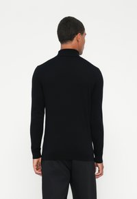 Czarna longsleeve polo z prążkowanym kołnierzykiem i mankietami. Miękka faktura i dopasowany krój. Zdjęcie z tyłu, pokazujące minimalne detale.