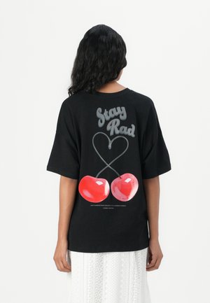 Black cotton t-shirt featuring a graphic design with the text "Stay Rad" above two glossy red cherries and a heart shape.