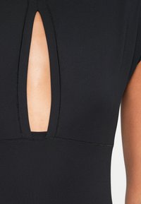 Body preto com recorte em forma de fechadura no peito, textura suave, mangas curtas e costuras contrastantes ao longo das emendas.