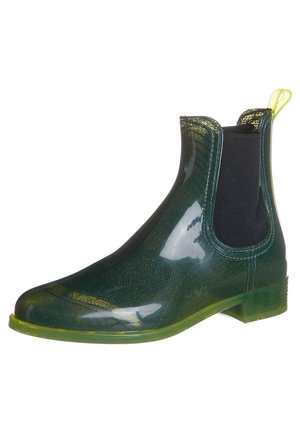 Bottines en caoutchouc vert avec une finition brillante, panneaux latéraux élastiques noirs et un talon translucide vert. Dotées d'une languette pour un enfilage facile.