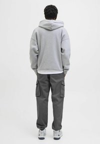 Grå oversized hoodie med snører i hætten, parret med mørkegrå cargo bukser med sidelommer. Båret med grå sneakers.