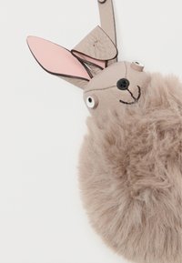 Triušio formos raktų pakabukas, pagamintas iš minkštos bežinės dirbtinės odos, su odiniu galvūgaliu, rožiniais ausų akcentais ir didelėmis plastikinėmis akimis.