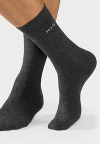 Dunkelgraue Knöchelsocken aus einem glatten, weichen Material; mit einem Logo (H.I.S) nahe der Oberkante in kontrastierendem Weiß.