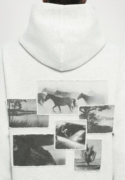 Haut à capuche gris clair avec un grand design à l'arrière comportant plusieurs patchs photo en noir et blanc représentant des chevaux et des paysages. Détails texturés.