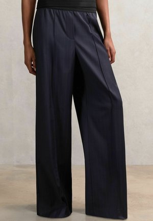 Pantaloni largi, cu dungi navy, având un elastic în talie de culoare neagră. Material neted cu dungi verticale, prezentând o croială relaxată și atentă.