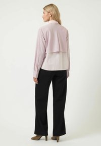 Ljust rosa skjorta med randig krage och manschetter, matchad med svarta vida byxor. Naturligt tyg, strukturerad silhuett och knappdetaljer.