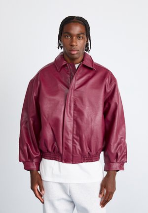 Bordeaux leren jack met een kraag, elastische tailleband en knoopsluiting. Beschikt over brede mouwen en een gladde, glanzende textuur.