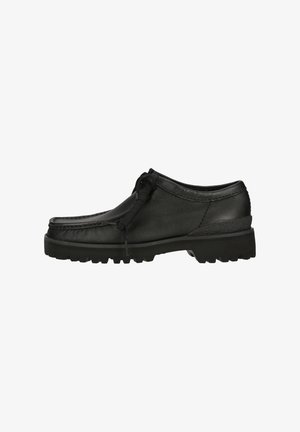 Chaussure décontractée en cuir noir avec semelle crantée épaisse, couture moc toe, et lacets noués, vue de l'intérieur sur fond blanc.