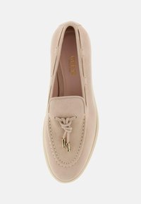 Bežiniai zomšiniai slip-on bateliai su apvalia nosimi, dekoratyvine mazgo nėrinių detalė, auksinės spalvos metalinės detalės ir baltas guminis padas.
