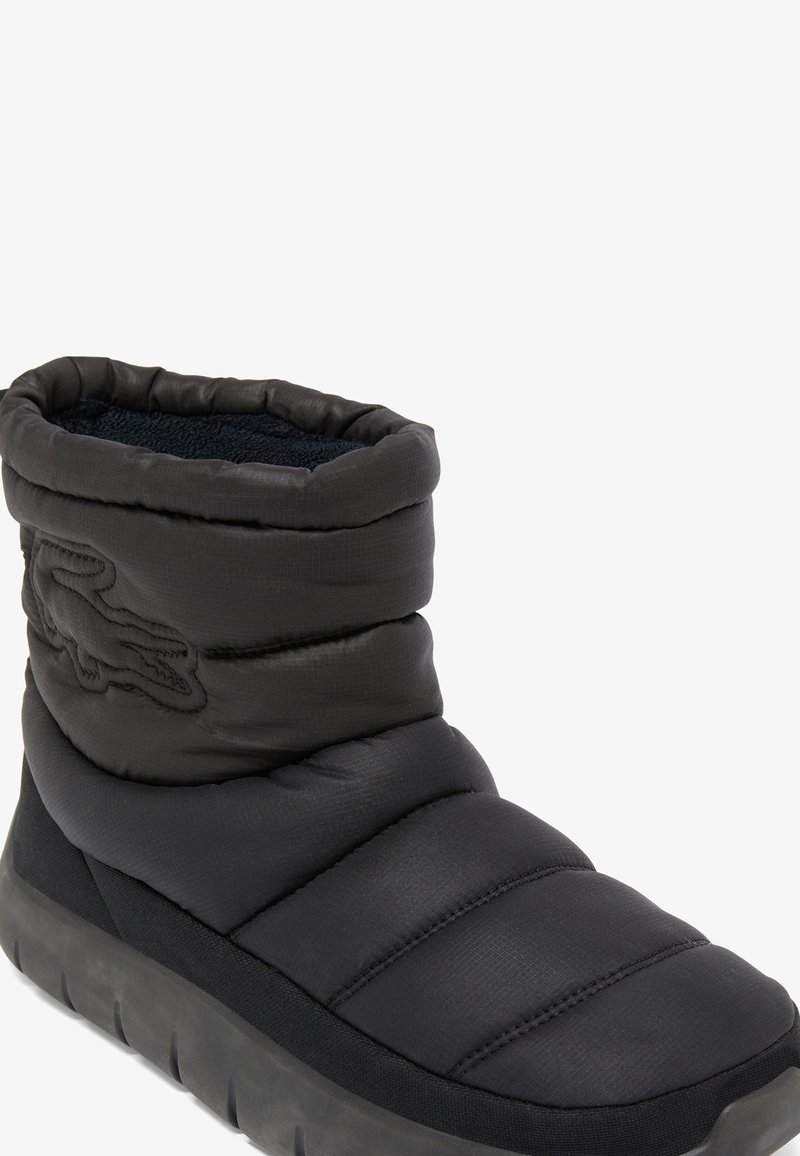 Schwarze isolierte Knöchelstiefel mit einem puffigen Design, strukturiertem Stoff und einer dicken Sohle. Verfügt über ein auffälliges Markenlogo an der Seite.