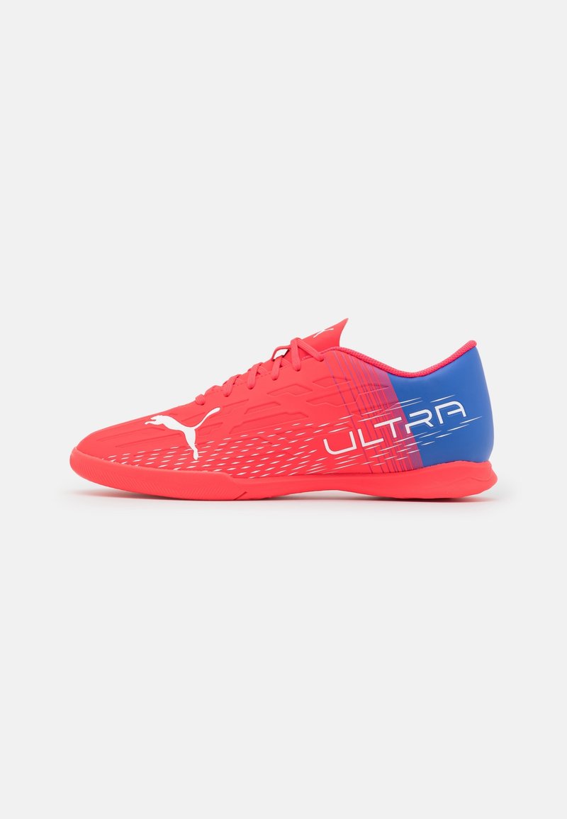 Baskets athlétiques rouges et bleues avec une tige texturée, comportant le mot "ULTRA" en lettres blanches en gras, design épuré avec des lignes dynamiques.