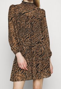 Robe en imprimé animal marron avec un col montant, taille froncée, longues manches bouffantes et une jupe évasée, fabriquée en tissu léger.
