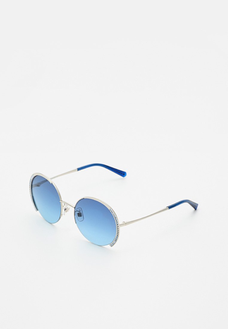 Lunettes de soleil rondes avec une monture en argent, des verres dégradés bleus et des accents bleus sur les branches, ornées de pierres scintillantes le long du bord de la monture.