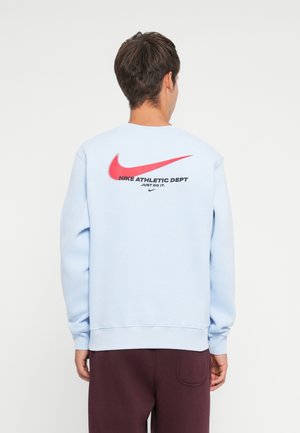 Light blue sweatshirt with a crew neckline, featuring a large red Nike Swoosh and the text "Nike Athletic Dept. Just Do It." on the back.