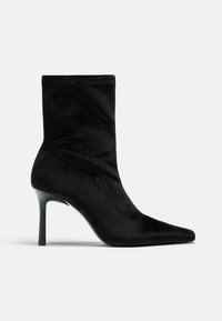 Czarne materiałowe botki za kostkę z ostrym noskiem, wysokim obcasem w kształcie szpilki i gładką teksturą. Posiadają dopasowany, luźny fason.