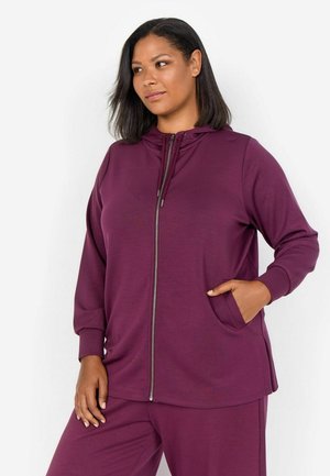 Haut à zip violet en tissu doux, doté d'une capuche, de poches latérales et d'une coupe décontractée. Associé à un pantalon assorti.