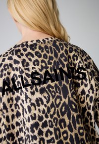 Kurzärmeliges Oberteil mit Leopardenmuster in Beige und Schwarz, mit einem markanten "ALLSAINTS"-Logo auf dem Rücken. Weicher Stoff und lockere Passform.
