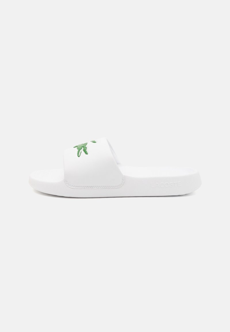 Sandale à glissière blanche avec une large bride arborant un logo crocodile vert et une semelle intérieure texturée, marquage Lacoste sur le côté de la semelle.