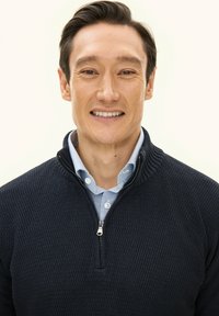 Granatowy sweter z teksturowanym splotem, zapinany na zamek do połowy wysokości, zestawiony z jasnoniebieską koszulą w kratę. Luźny fason z prążkowanym kołnierzem i mankietami.