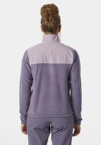 Fioletowa polarowa kurtka z wysokim kołnierzem, zaprojektowana w technice color-blocking z jaśniejszą górną częścią, miękka w dotyku, z długimi rękawami.