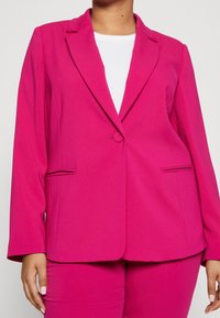 Fuchsia blazer i mjukt tyg, med slagkrage, enkel knäppning och sidofickor. Långa ärmar med en skräddarsydd passform.