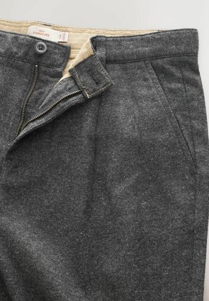 Graue Stoffhose mit einer strukturierten Oberfläche, ausgestattet mit Reißverschluss, Knopfverschluss und Seitentaschen. Innenfutter in heller Farbe.