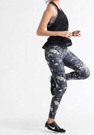 Canottiera atletica nera senza maniche abbinata a leggings fantasia blu navy e grigi. I leggings presentano un design camo digitale e sono di lunghezza alla caviglia.