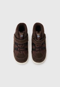 Bruna högsneakers med en överdel i mocka och textil, svarta elastiska remmar, en kardborrerem och en vit gummisula.