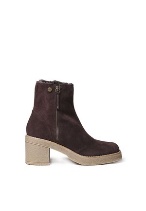 Dark brown suede ankle boot with side zipper, round toe, block heel, and beige textured sole, featuring a small metal logo button near the zipper.