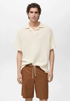 Stickad krämfärgad polo med korta ärmar, texturerad tyg, kombinerad med bruna shorts med elastisk midja. Enkel kragdesign, avslappnad passform.