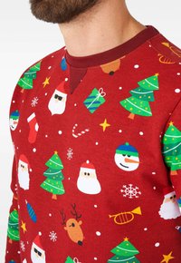 Suéter navideño rojo que presenta patrones multicolores de Papá Noel, árboles de Navidad, regalos y copos de nieve. Cuello redondo y puños acanalados.