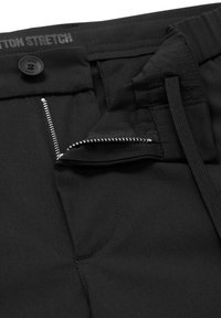 Svarta bomullssträcktrosor med dragkedja, silverfärgad dragkedja, knappstängning och framfickor med en mjuk textur.