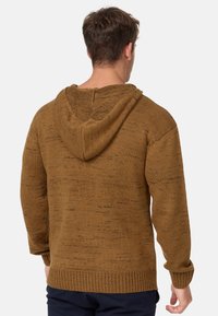 Hoodie en tricot marron avec une finition texturée, comprenant une capuche, des poignets et un ourlet en côtes, mettant en avant une coupe ample et un design décontracté.