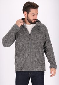 Grå zip-up huvjacka i ett strukturerat tyg, med huva, sidofickor och en liten logotyp på bröstet.