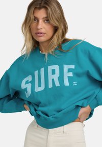 Turkusowy sweter z białym nadrukiem "SURF", luźny krój, ściągacze na rękawach i u dołu. Wykonany z miękkiego materiału, zaprojektowany z myślą o komforcie.