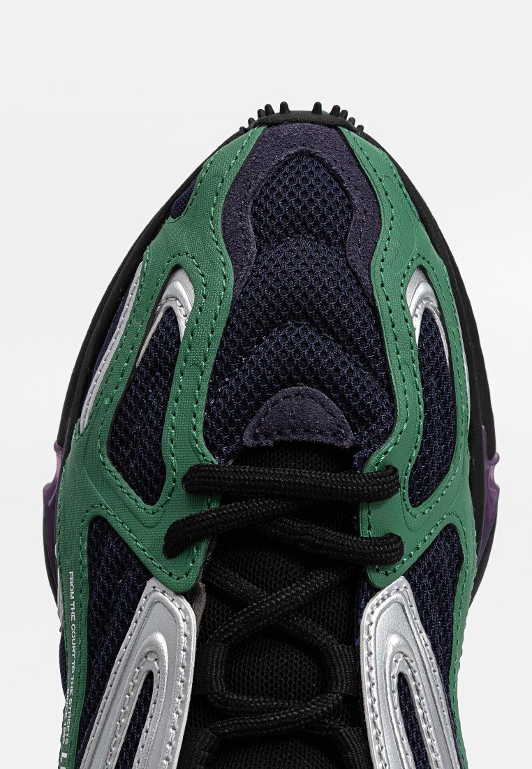 Baskets multicolores avec un dessus en mesh bleu marine, vert et violet, des accents argentés, un motif texturé et des lacets noirs.